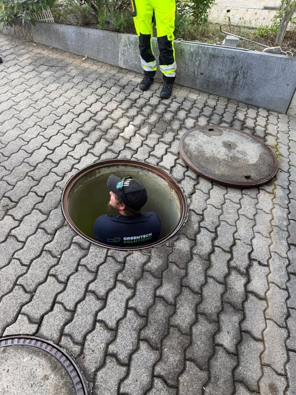 Mitarbeiter im Schachteinstieg kontrolliert den Zustand des Kontrollschachts von innen