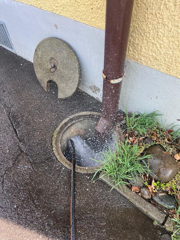 Schacht wird mit Hochdruck gespült, Wasser spritzt aus der Öffnung