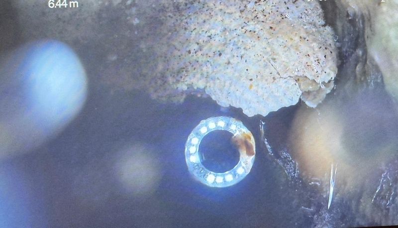 TV-Kamera-Aufnahme: Kalk- und Sinterablagerungen an der Wand einer Abwasserleitung, Zählerstand 6.44 Meter
